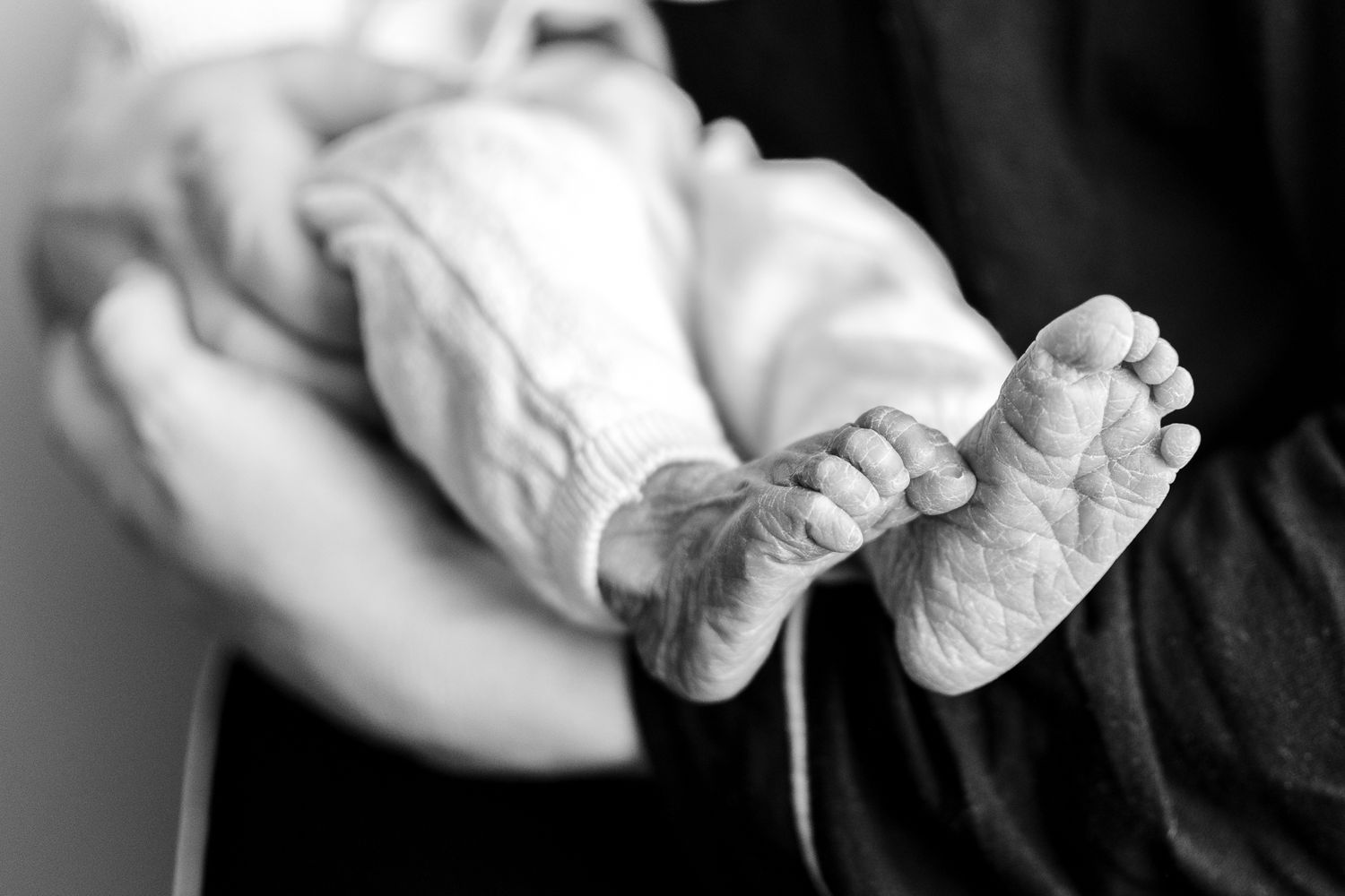 Close-up black and white photograph of tiny infant feet.