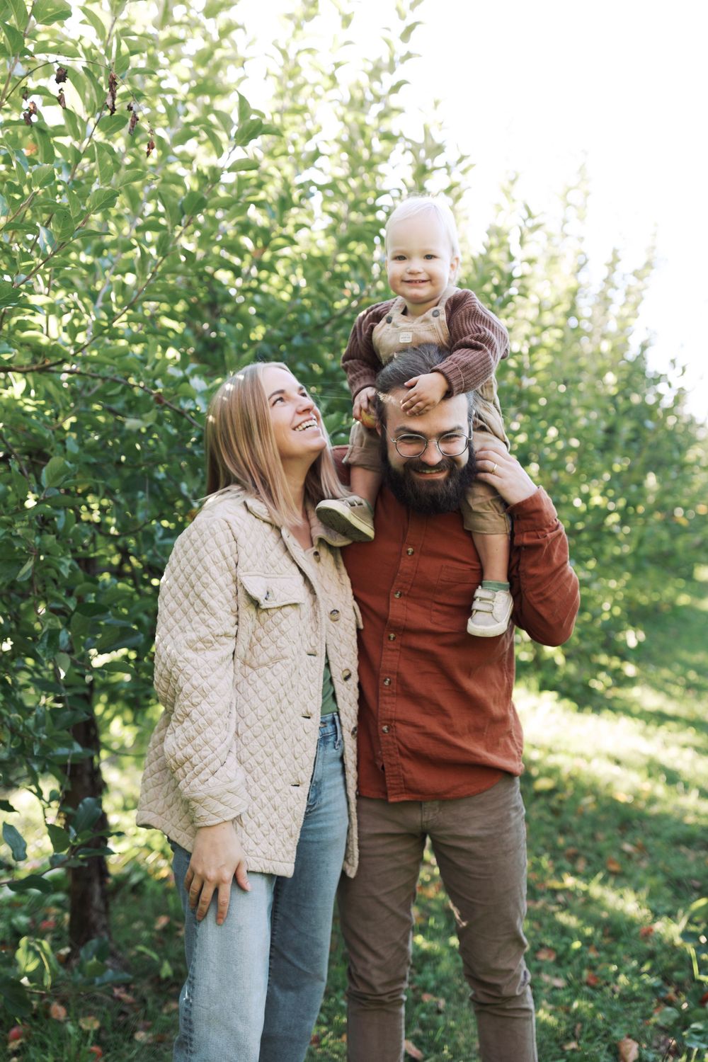 A happy family moment captured in an apple orchard on a sunny day.