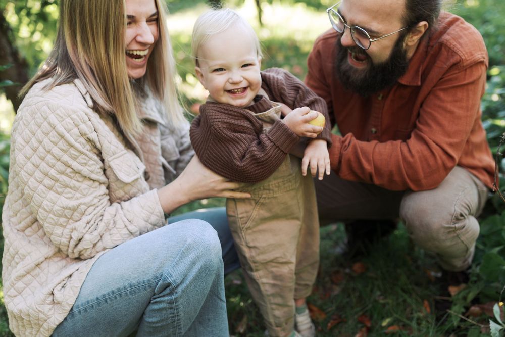 A joyful family sharing laughs together while apple picking in an orchard.