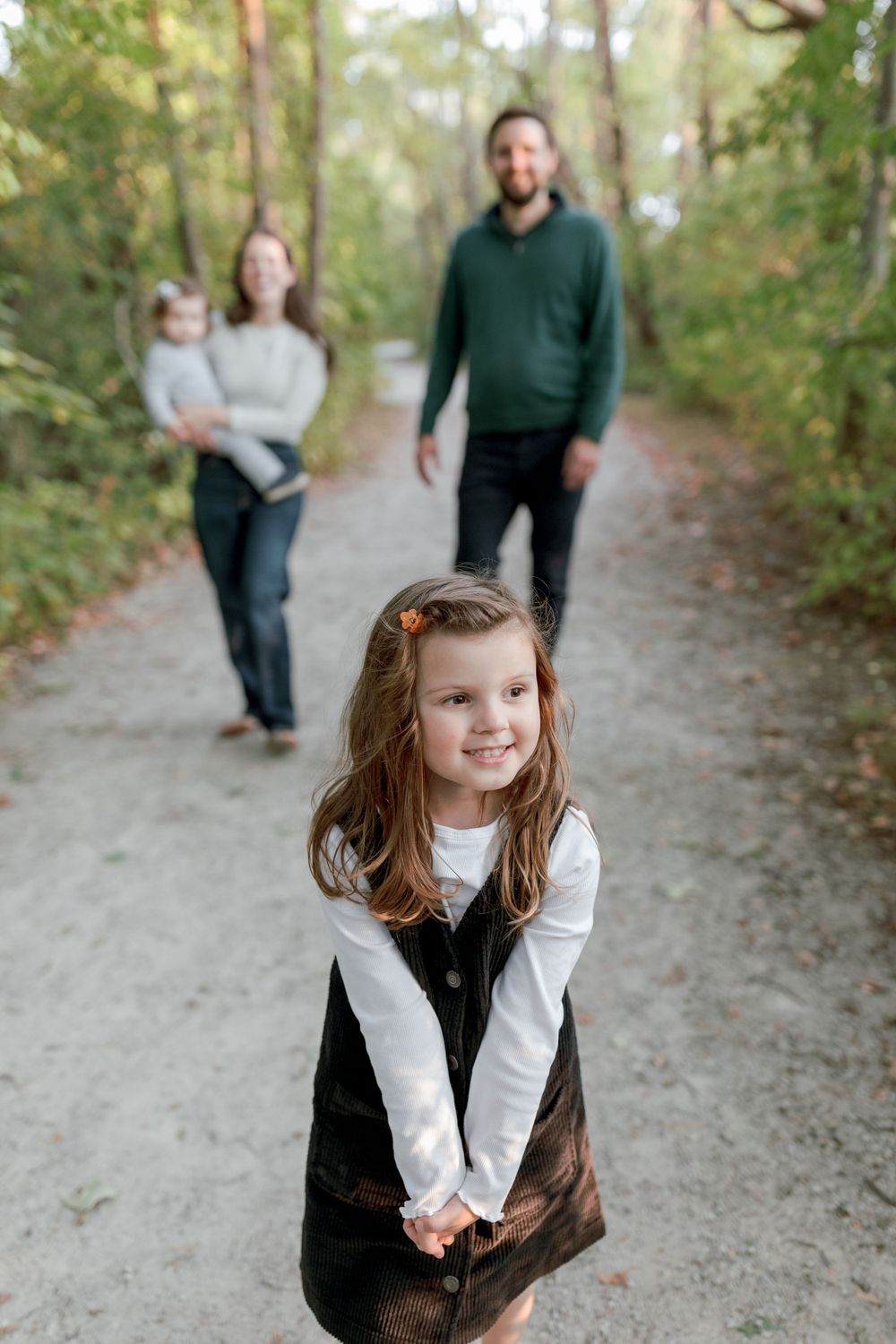 A sweet candid moment captured on a forest path during a family photoshoot.