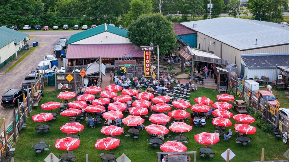 Aerial view of an outdoor venue with red and white Budweiser umbrellas covering crowded patio seating area.