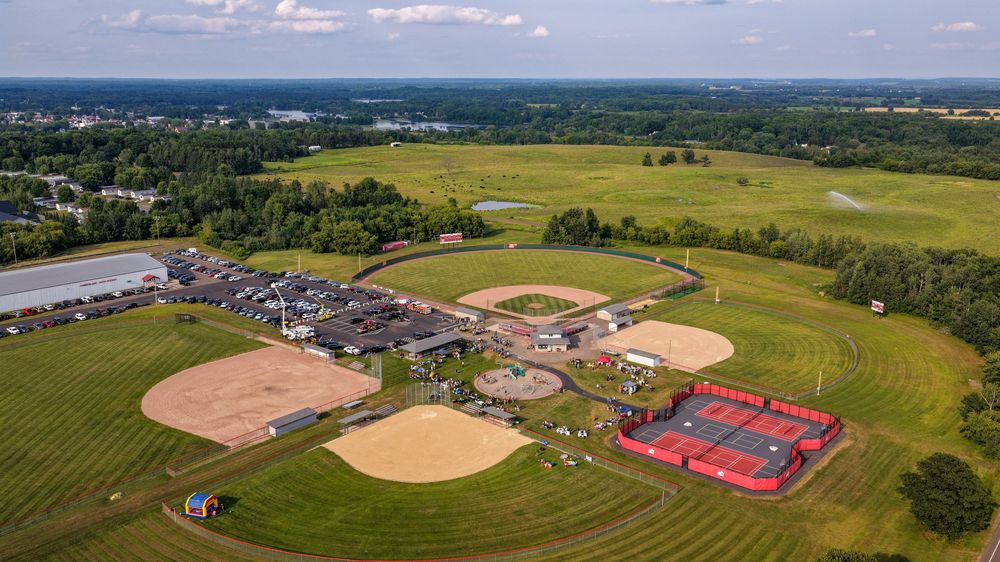 Aerial view of a multi-field sports complex with baseball and softball diamonds surrounded by lush green fields.