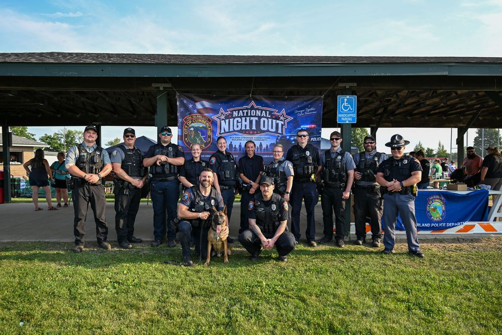 Law enforcement officers pose together at a National Night Out community event under a pavilion.