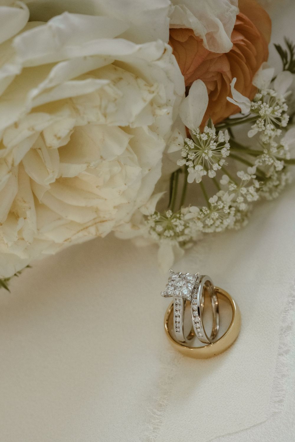 Wedding rings nestled among delicate white roses and baby's breath flowers.