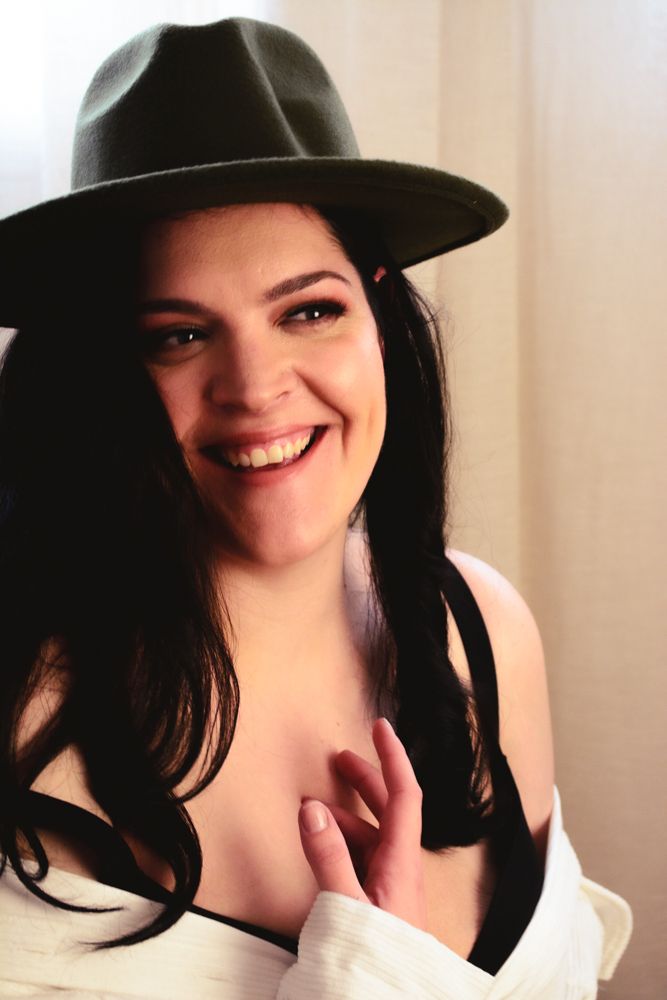 Indoor portrait featuring black hat and white top with natural lighting.
