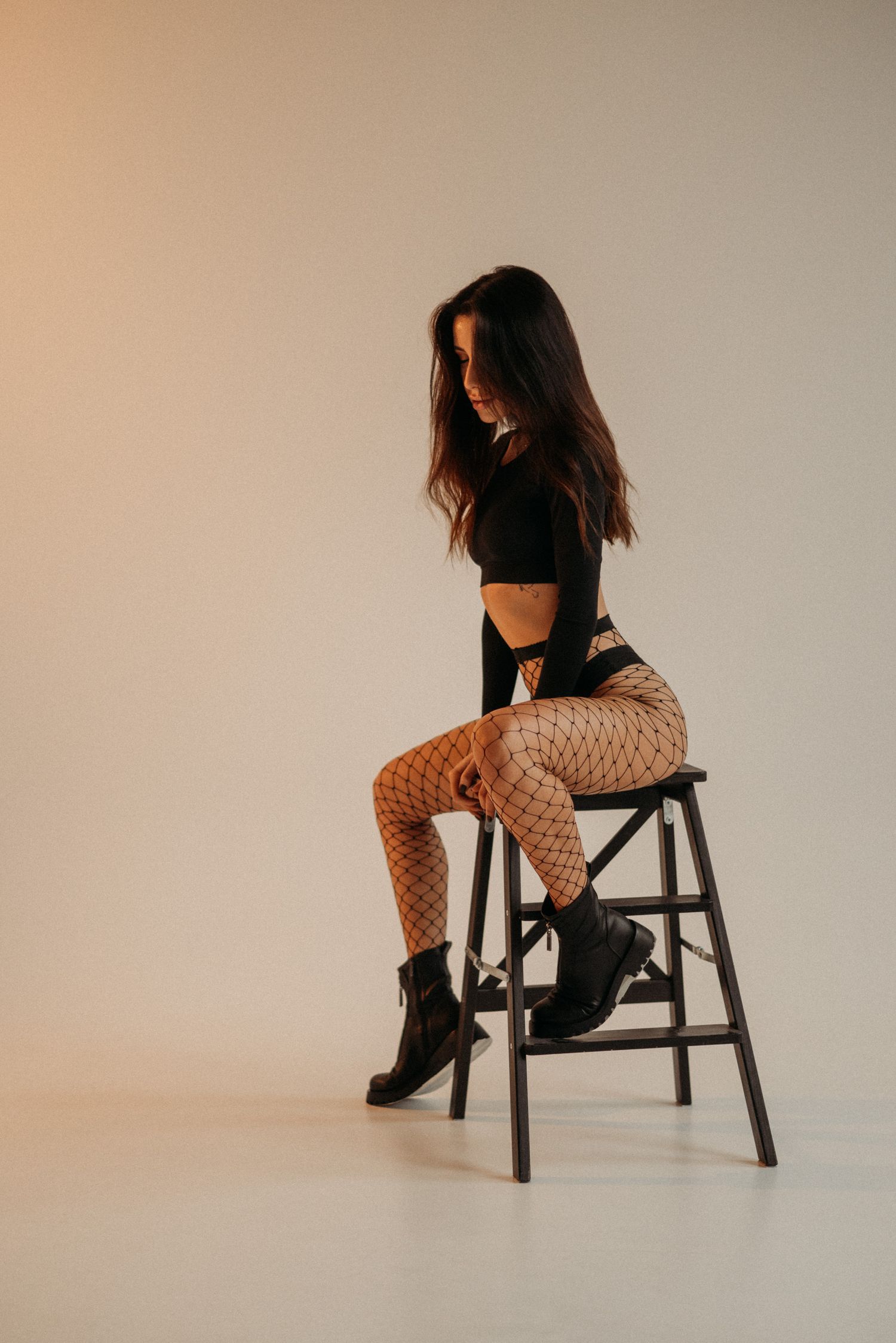 Artistic sequence of a figure in dark clothing sitting on a wooden chair against a light background.