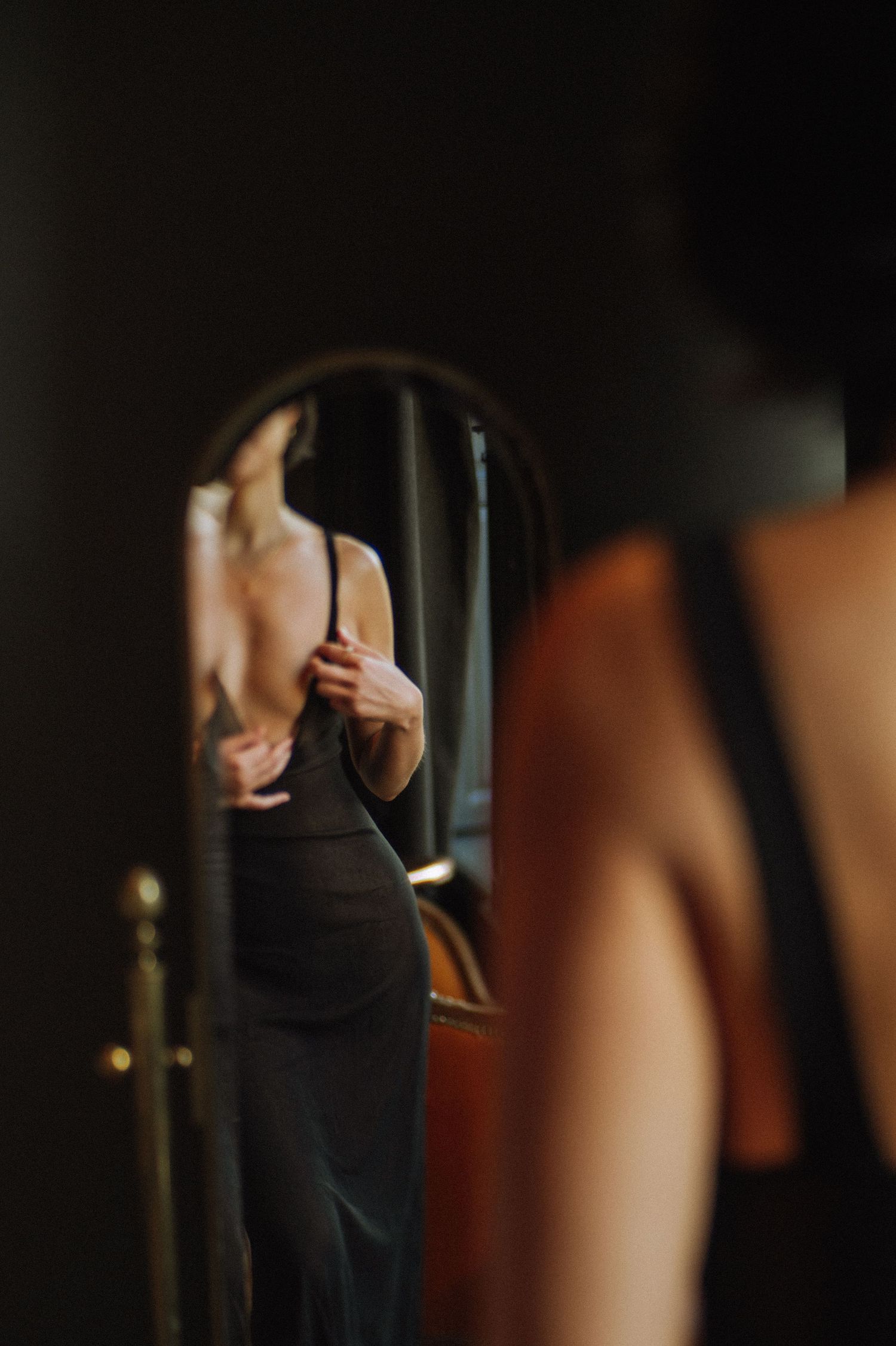 Artistic close-up shot of a figure in black against a dark background.
