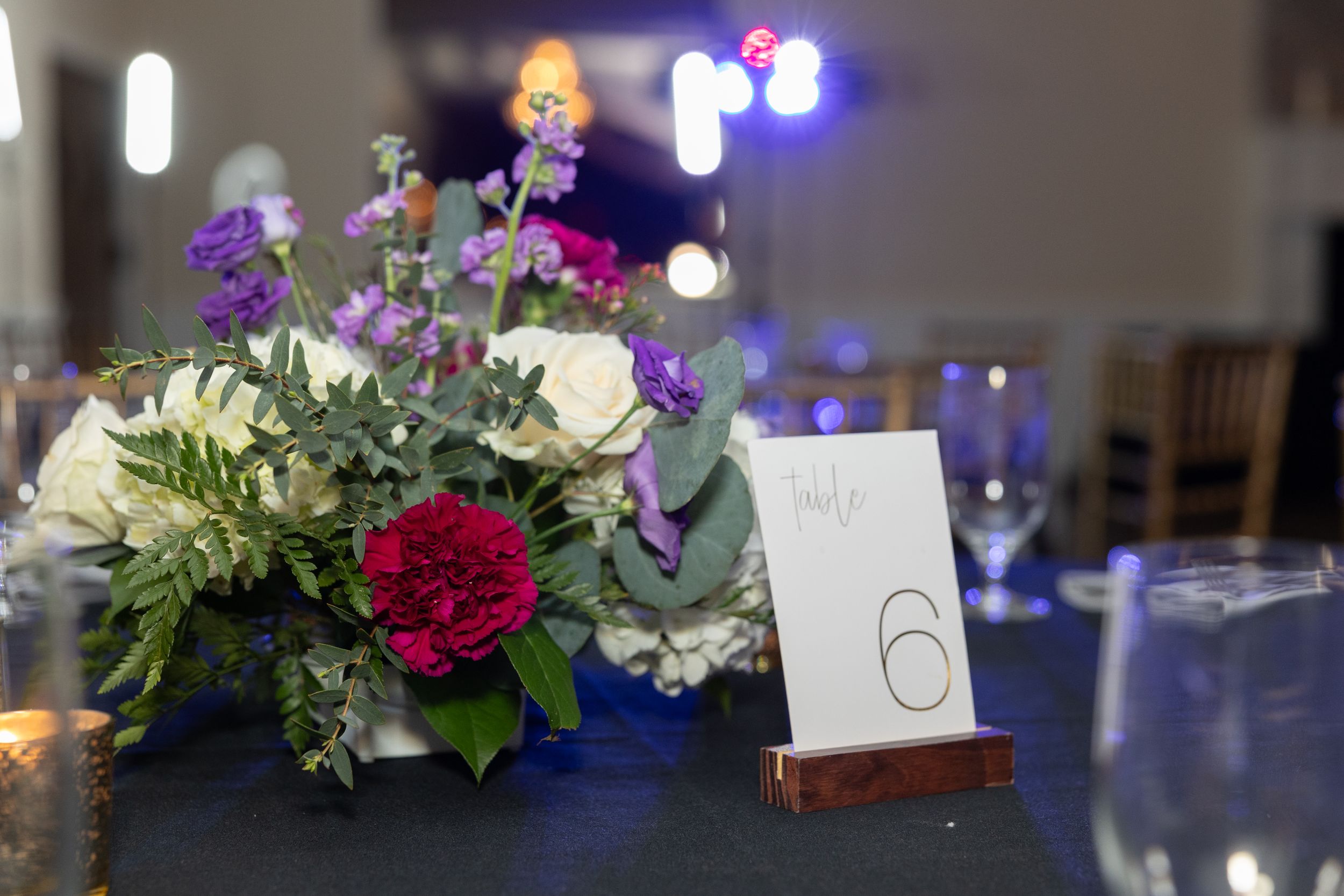 Elegant floral centerpiece with table number six at formal event setting.