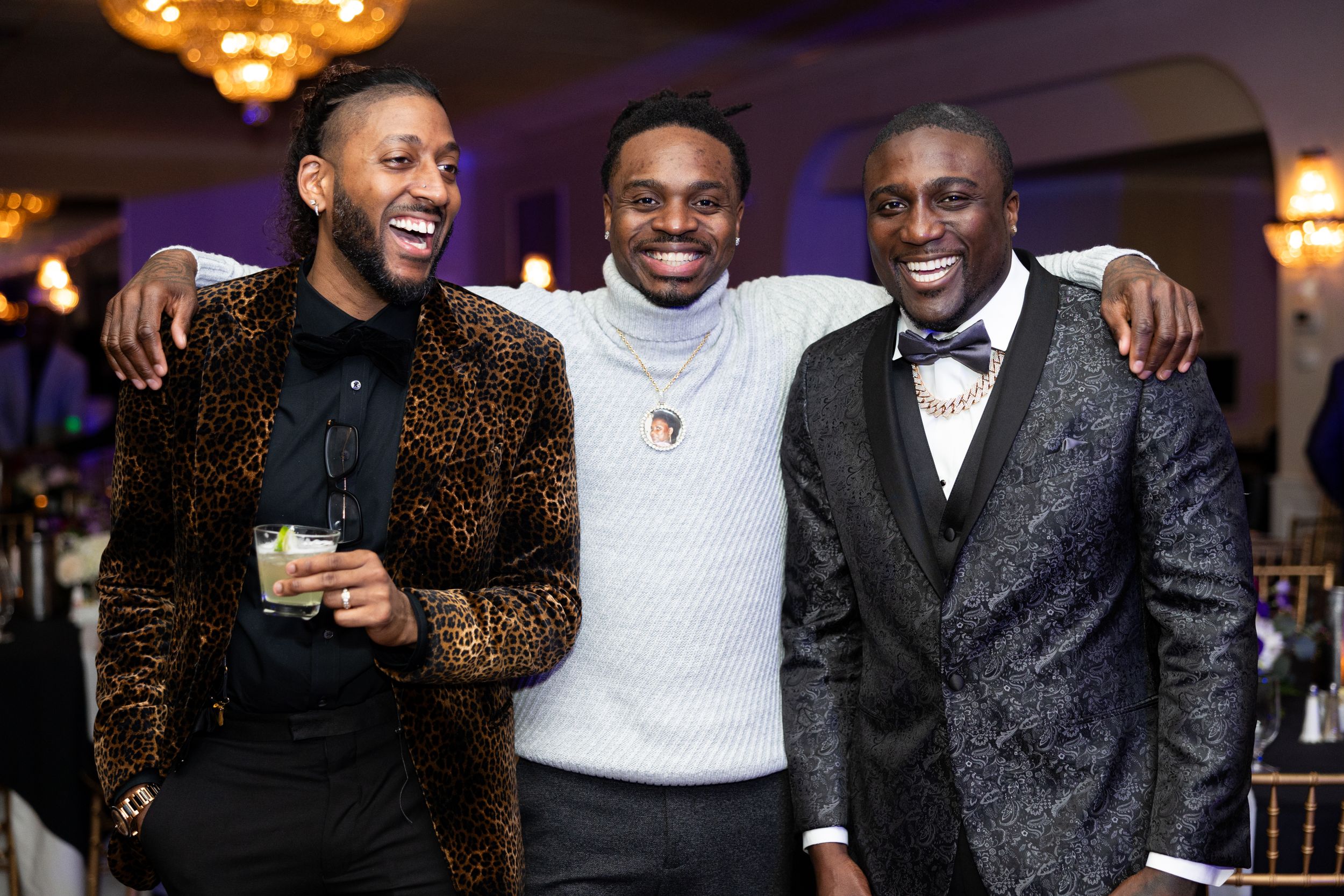 Three friends pose together in formal attire at an elegant evening event.