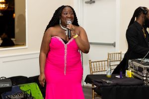 Entertainment performer in bright pink dress singing at formal event.
