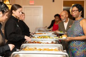 People serving themselves at elegant buffet line with multiple chafing dishes.