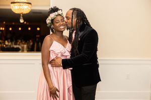 Romantic moment captured at formal event with pink dress and black suit.