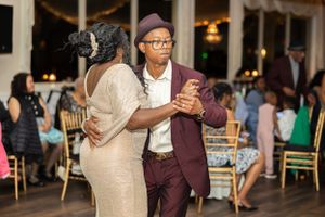 Couple dancing together at an elegant reception with chandelier lighting.