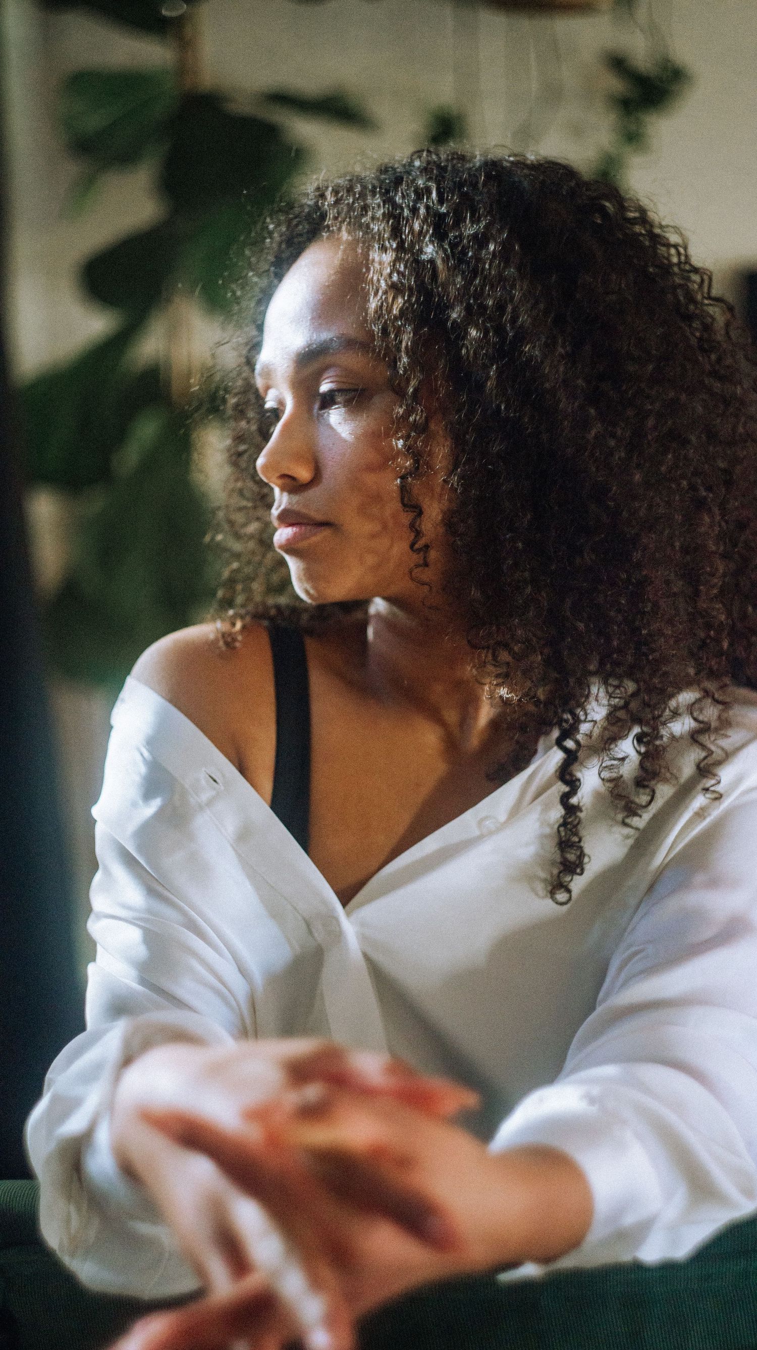 Portrait in white shirt with natural curly hair against soft indoor lighting.