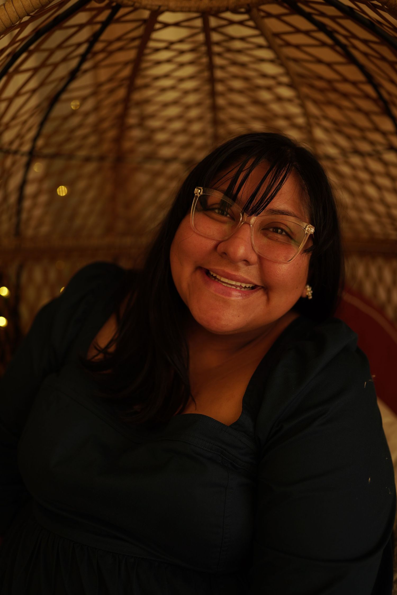woman smiling in a woven chair