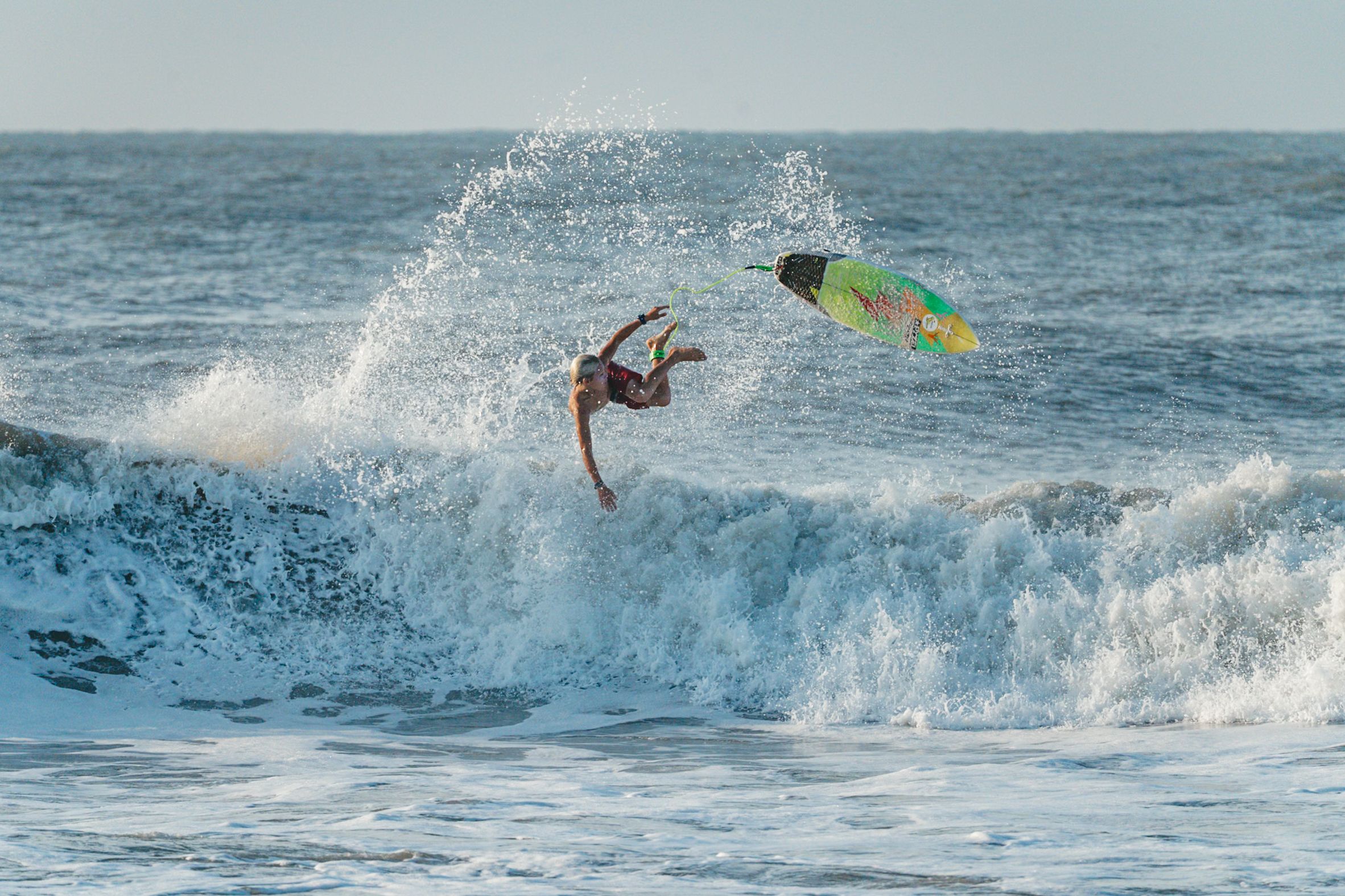 Dynamic sequence of surfer executing aerial tricks above breaking waves.