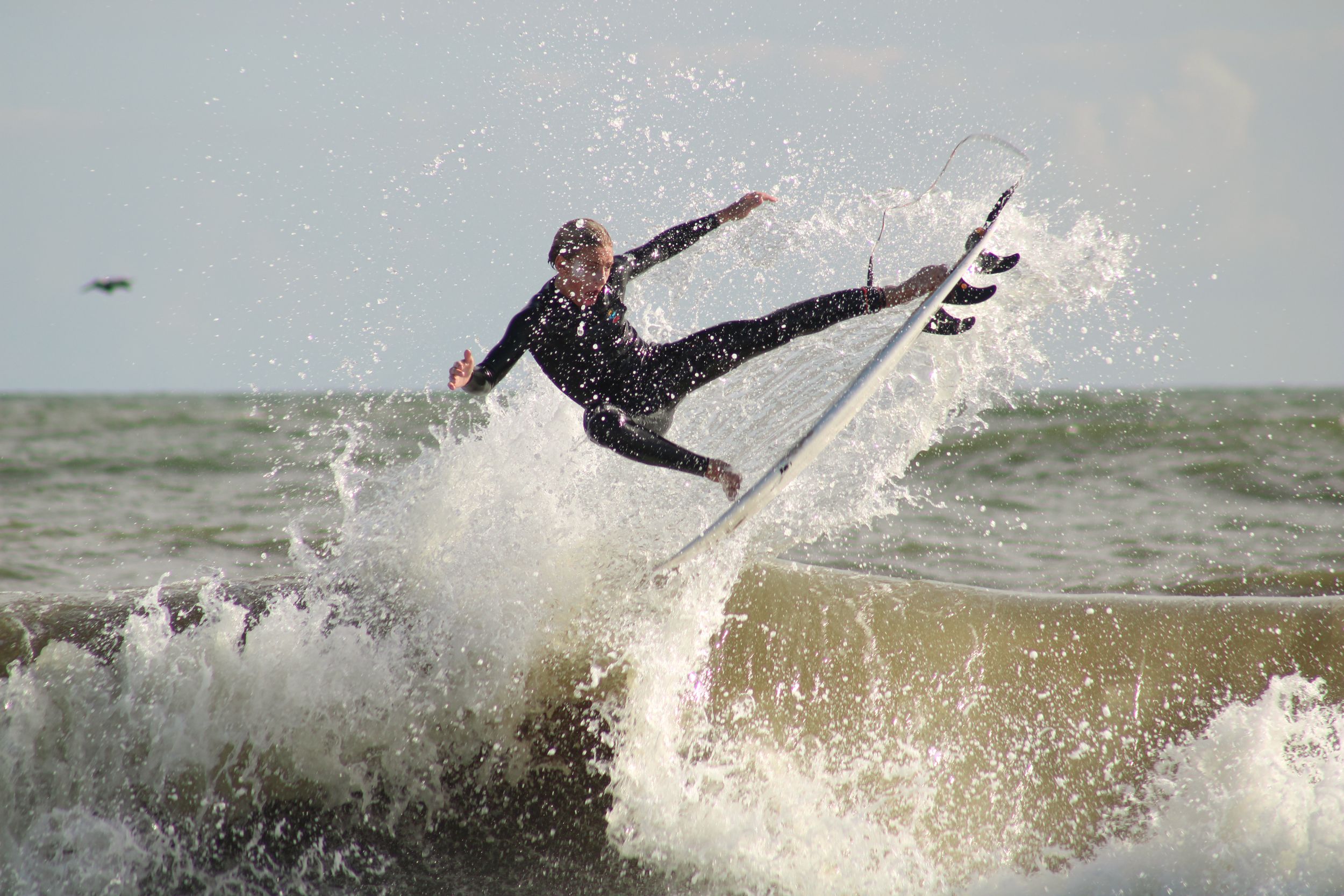 A wetsuit-clad surfer launches high above the wave during an aerial maneuver.