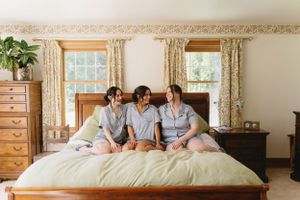Three people in matching light blue pajamas sit together on a bed.