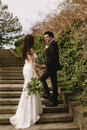 Couple sharing a romantic moment on stone garden steps with greenery backdrop.
