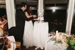 Couple cuts their elegant white wedding cake together at reception.