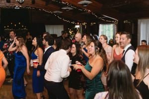 Wedding reception guests dancing under string lights in an indoor venue.