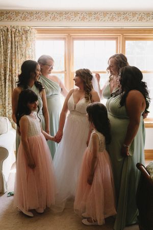 Wedding party with bridesmaids in sage green dresses and flower girls in pink tulle.