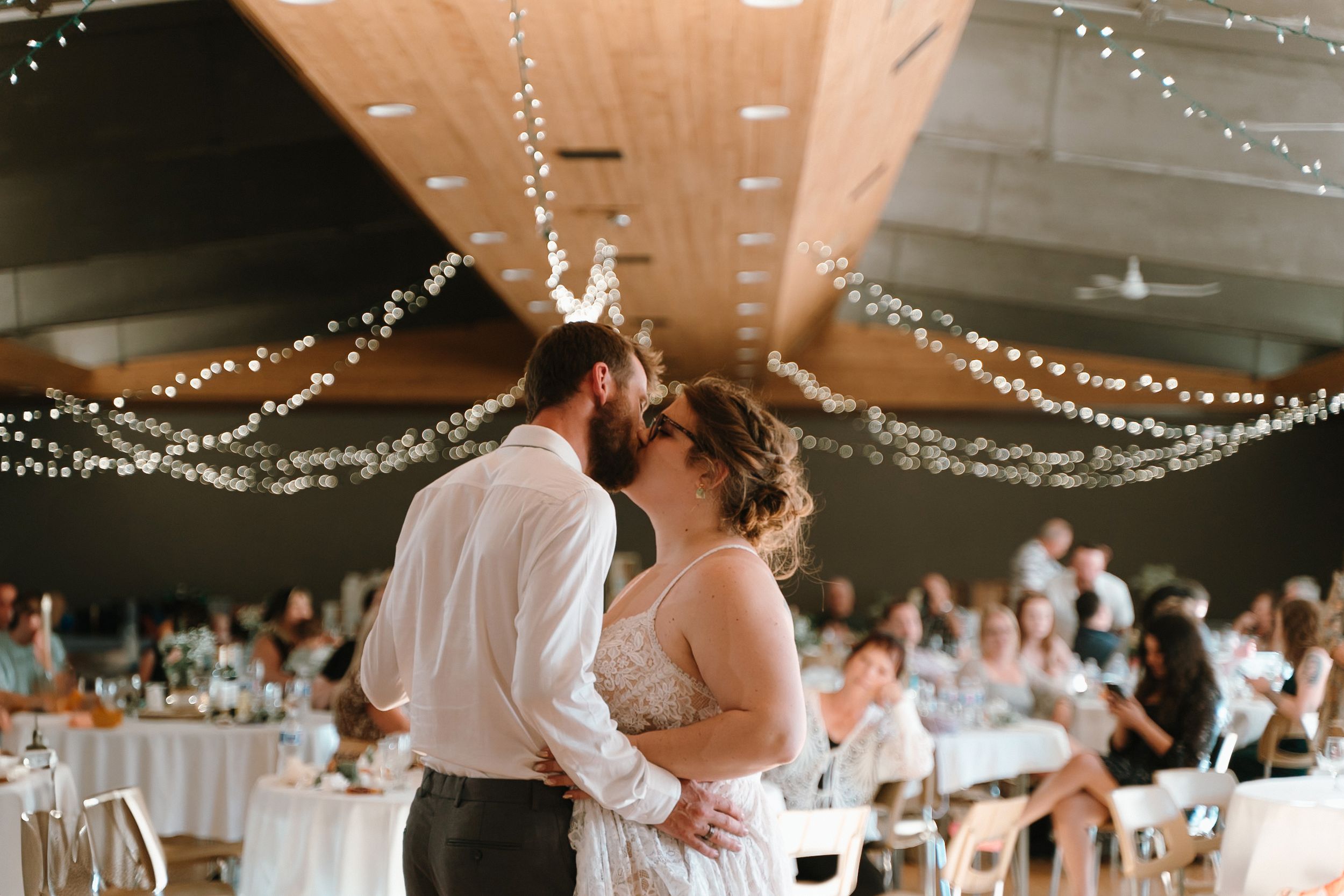Wedding couple sharing their first dance under twinkling lights at reception venue.