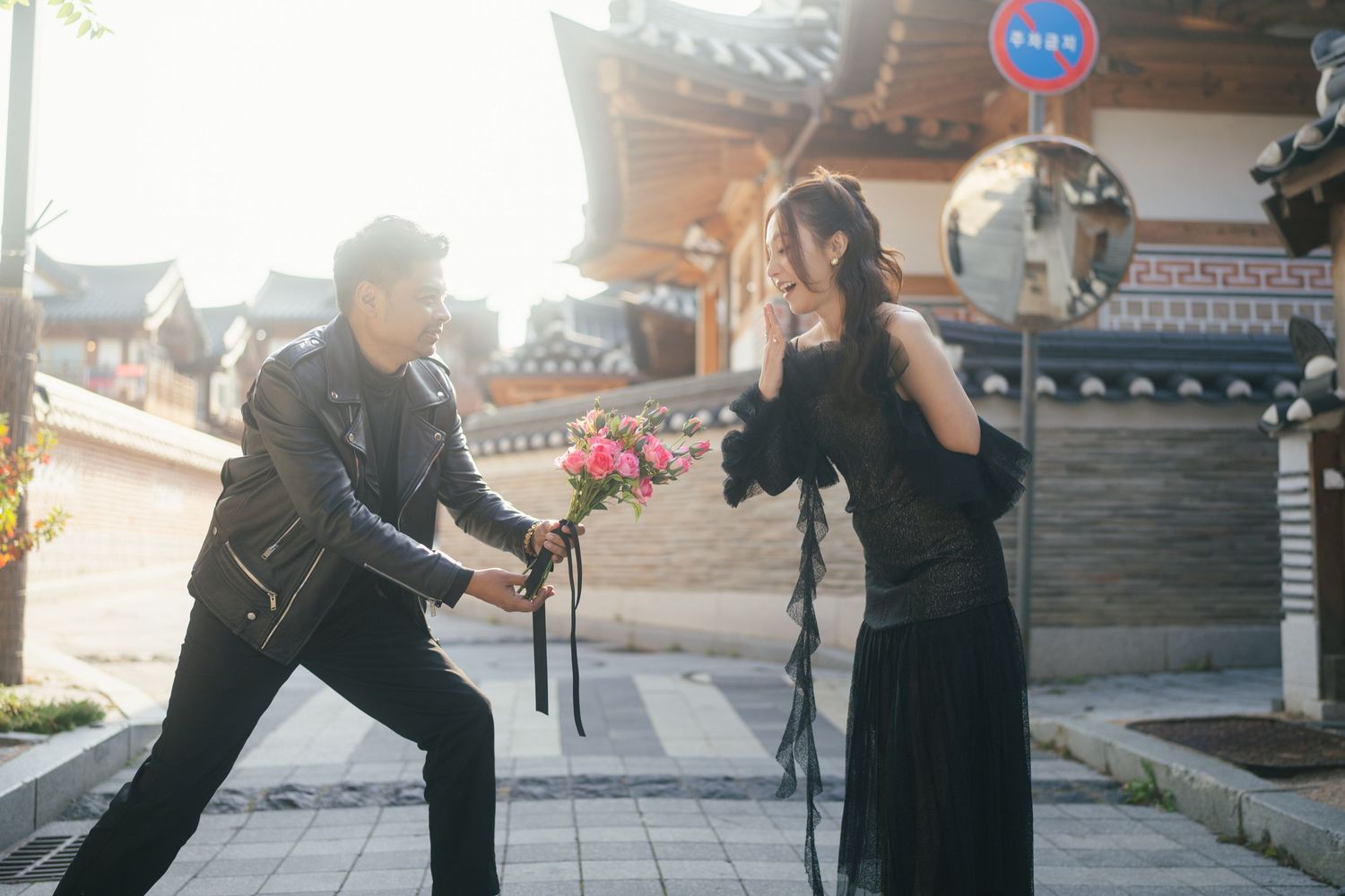 Martial arts practitioners demonstrate a sequence of combat moves in front of a traditional Asian temple building.