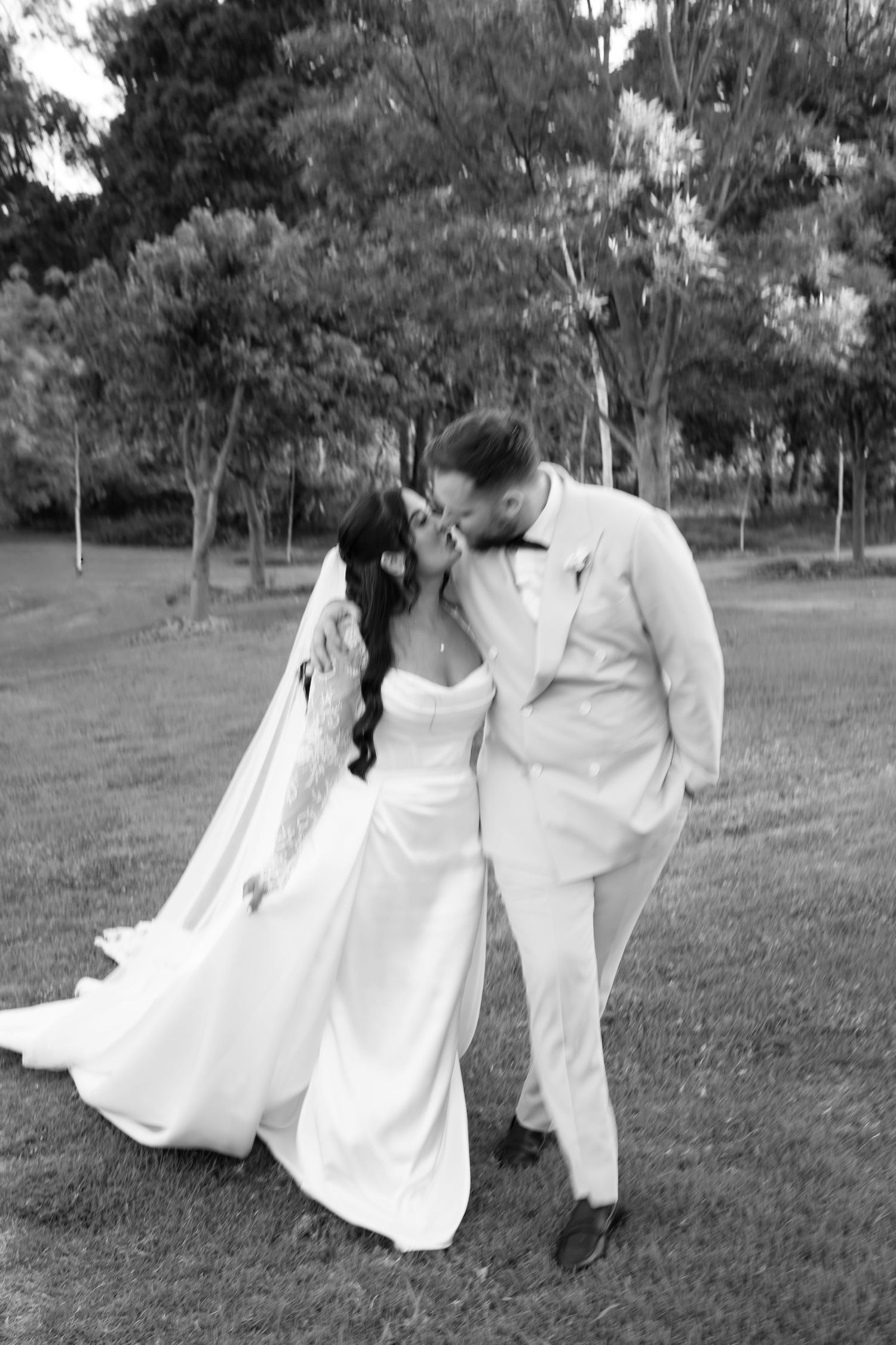 A romantic black and white photo series showing a couple in wedding attire dancing and dipping in a grassy outdoor setting.