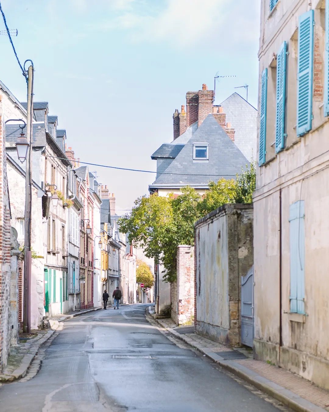 Quiet French street lined with pastel houses and soft morning light after rain.