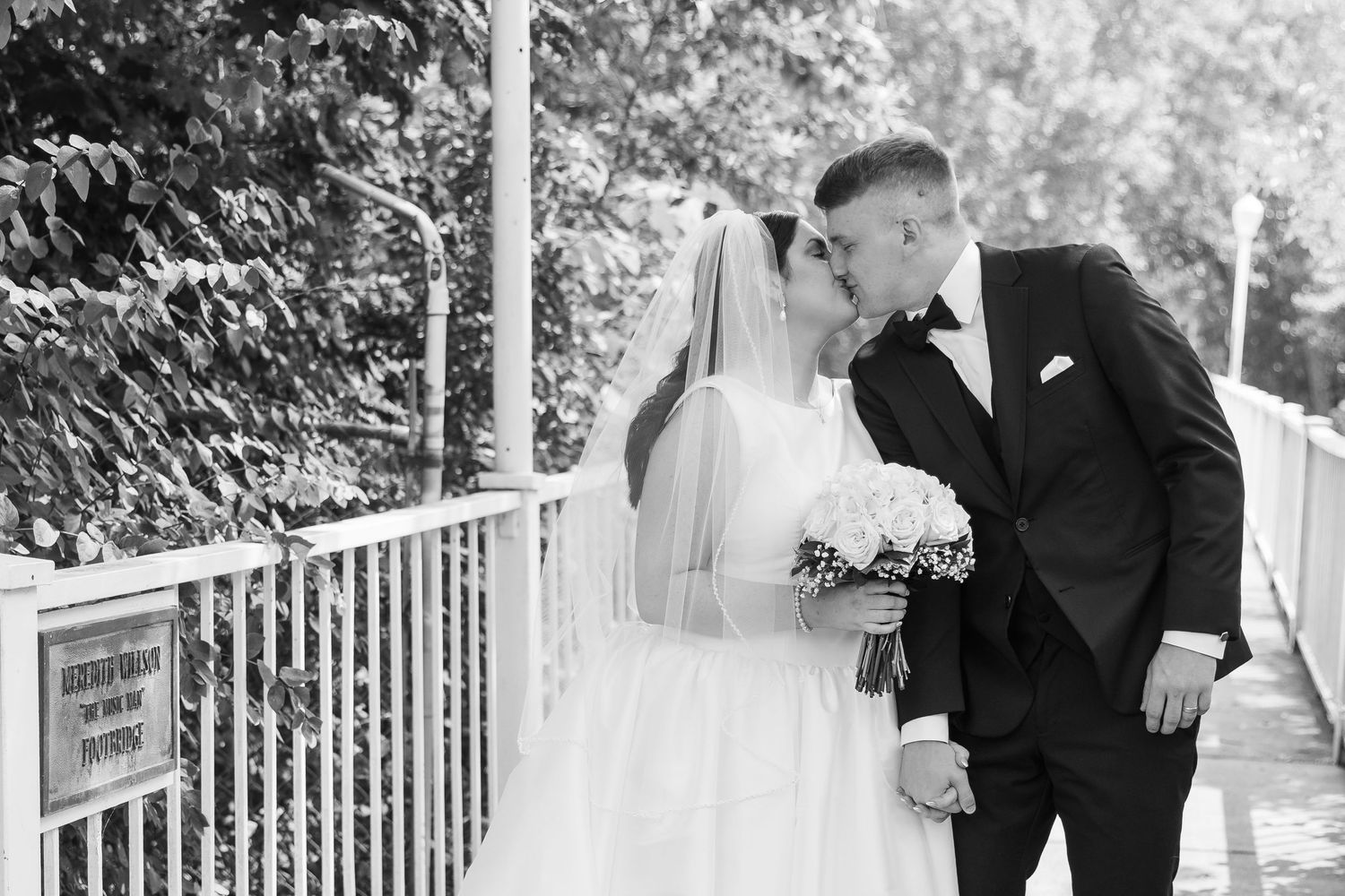 A bride and groom share an intimate moment during their outdoor wedding ceremony on a white porch railing.