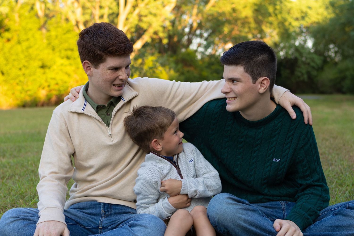 A relaxed family portrait session in a field with golden autumn foliage in the background.