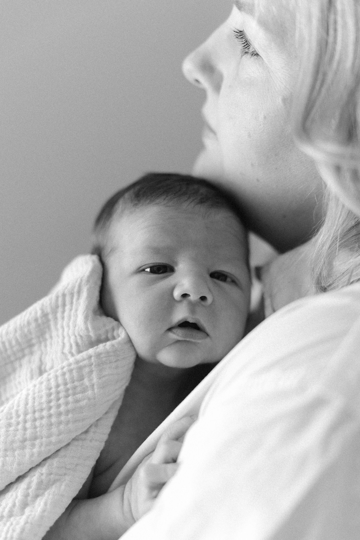 Newborn photos of baby gently cuddled with mom during a California studio shoot