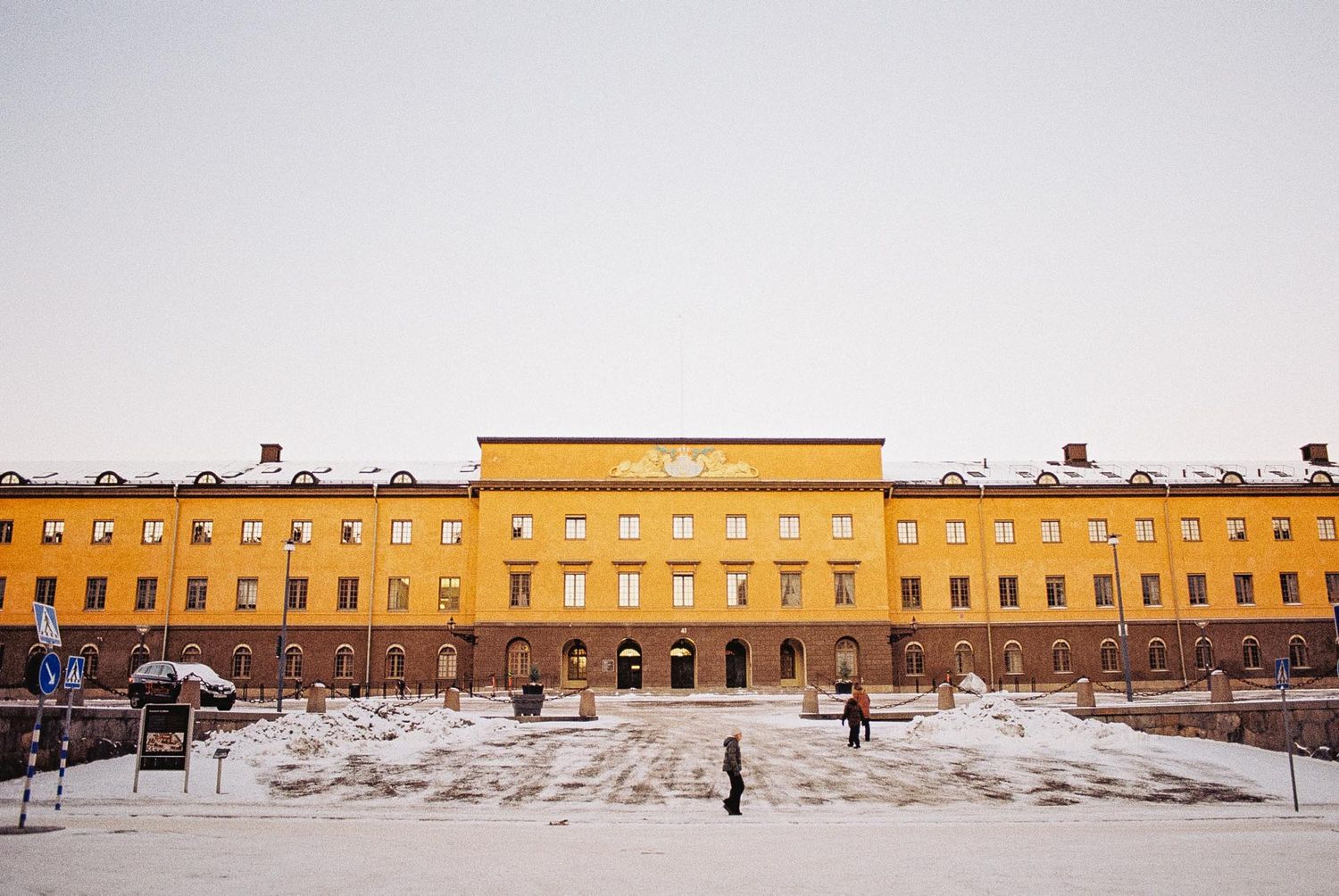 A large yellow historic building with snow-covered grounds and a symmetrical facade in winter.