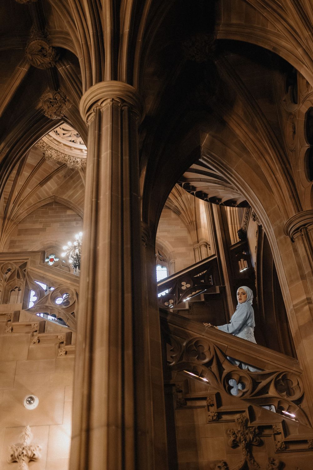 Gothic cathedral interior showing vaulted stone ceilings and architectural details in warm lighting.