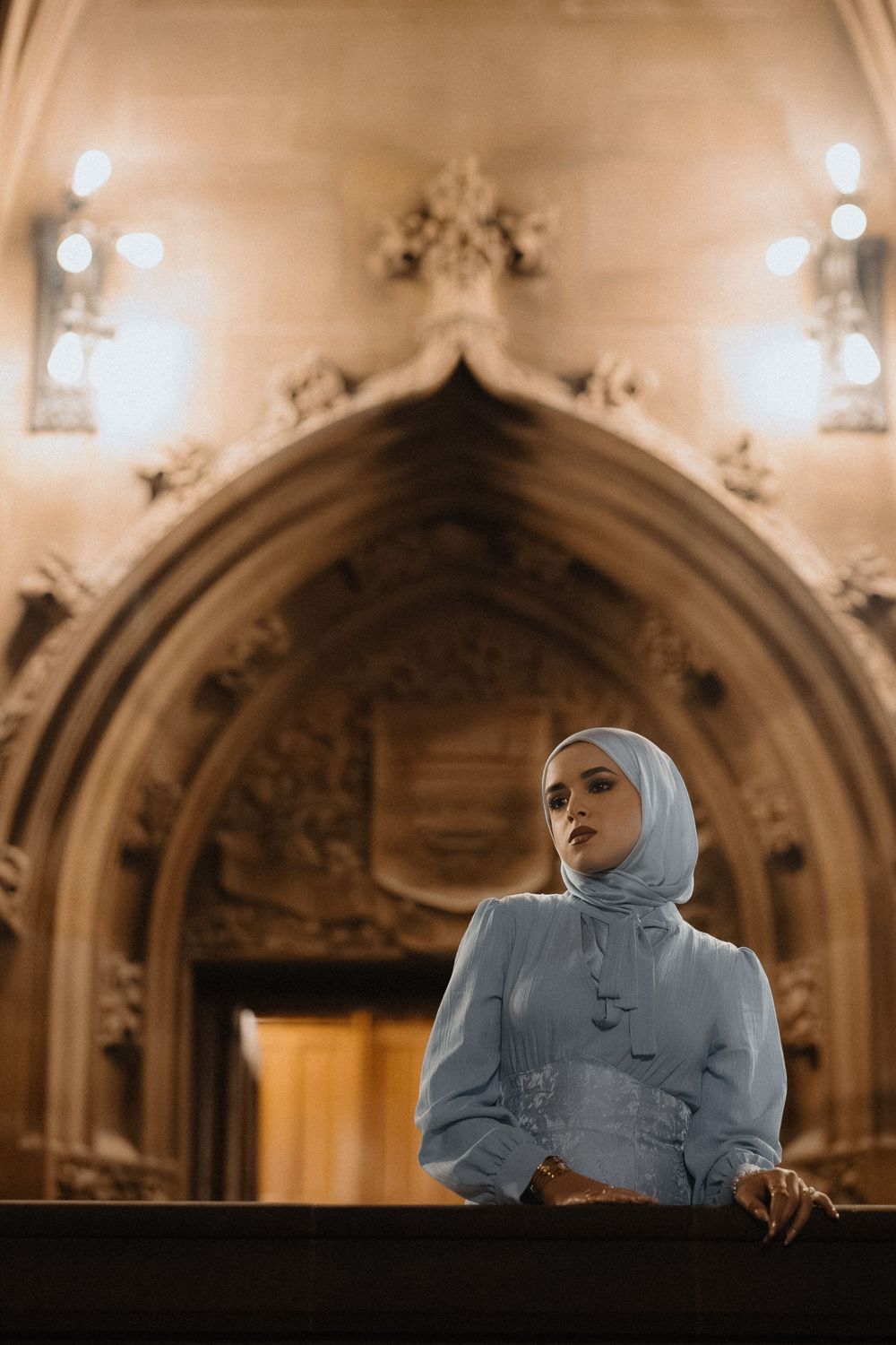 Atmospheric portrait in a grand cathedral setting with arched ceilings and warm lighting.