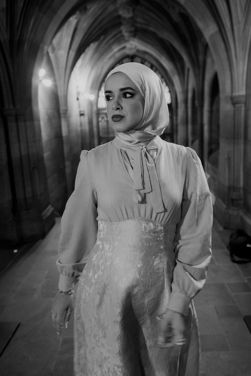 Artistic black and white photo captures ethereal movement in gothic church corridor.