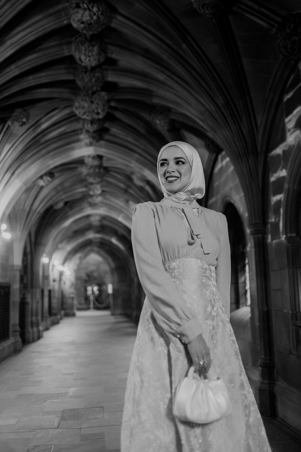 A series of black and white photos showing a figure in white attire walking through a gothic stone archway corridor.