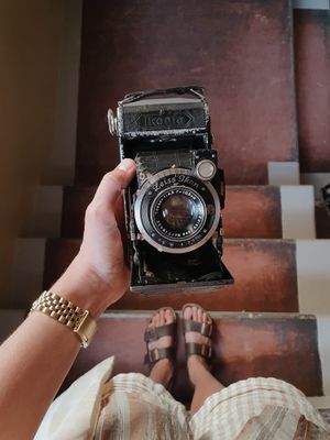 A vintage camera is held against a brown wooden background in a series of connected shots showing different angles.