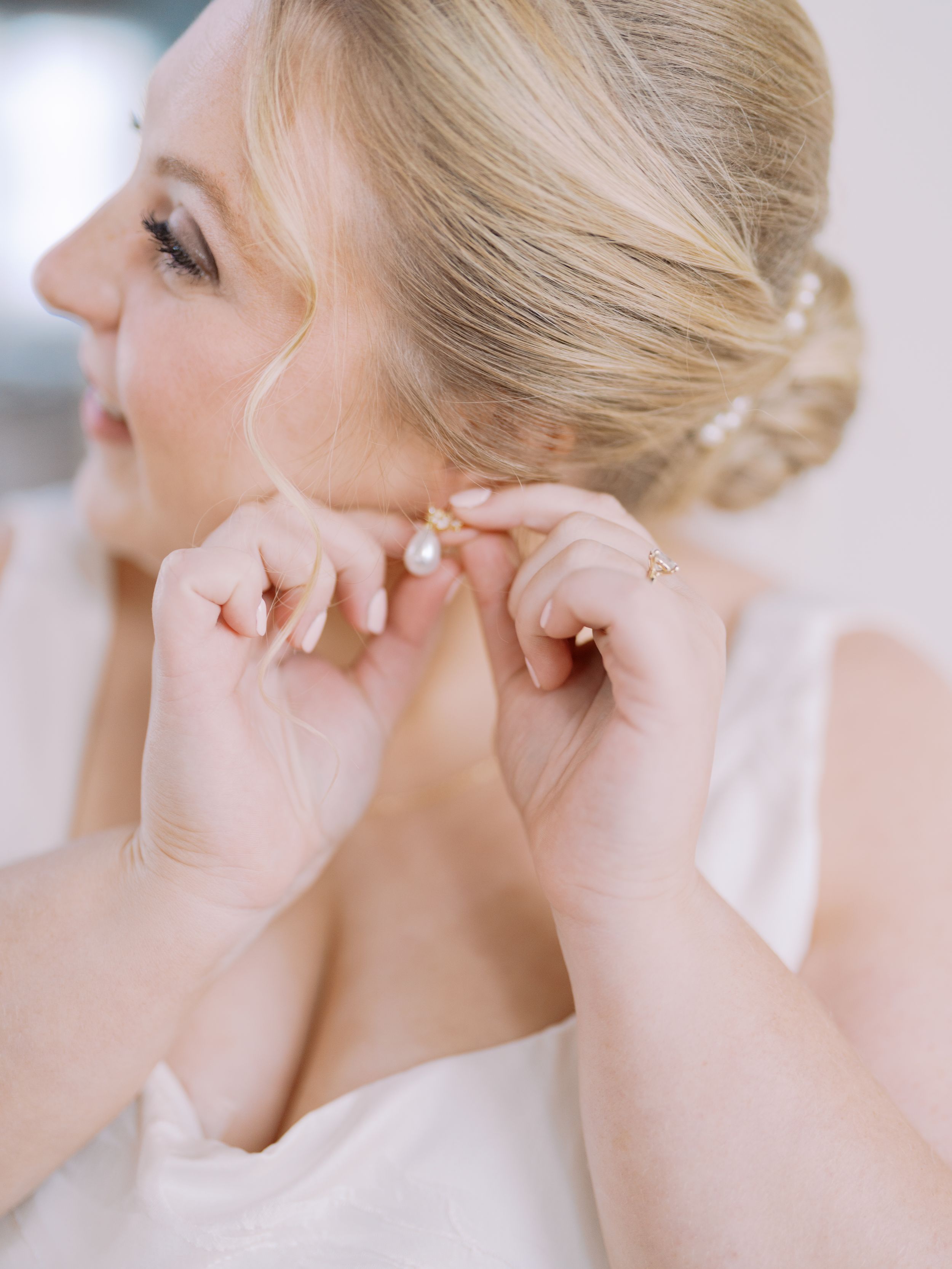 A series of four photos showing delicate earrings being placed on an ear against a soft white background.