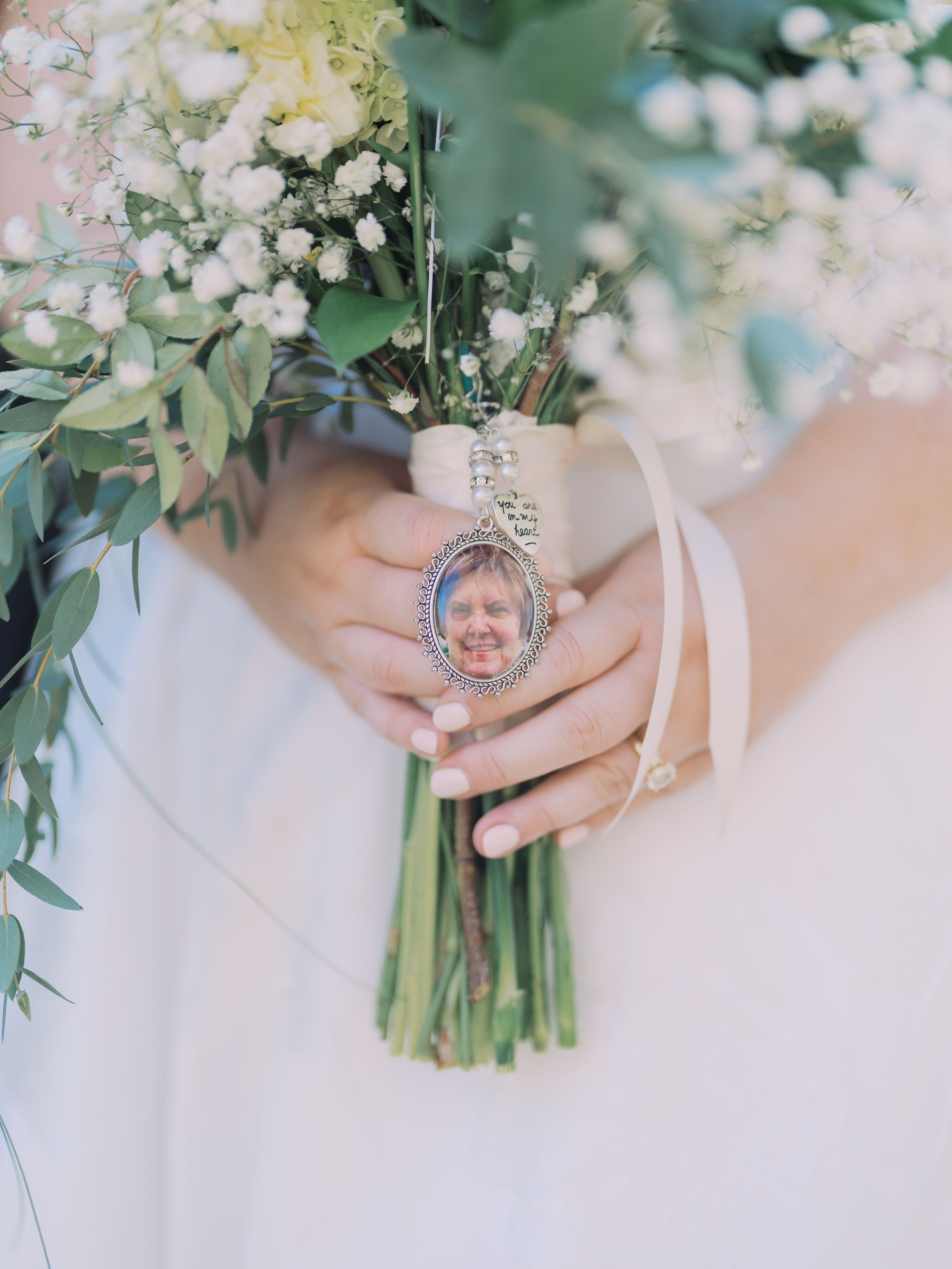 Close-up view of delicate white floral wedding bouquets with greenery and ribbon details in a soft, romantic style.