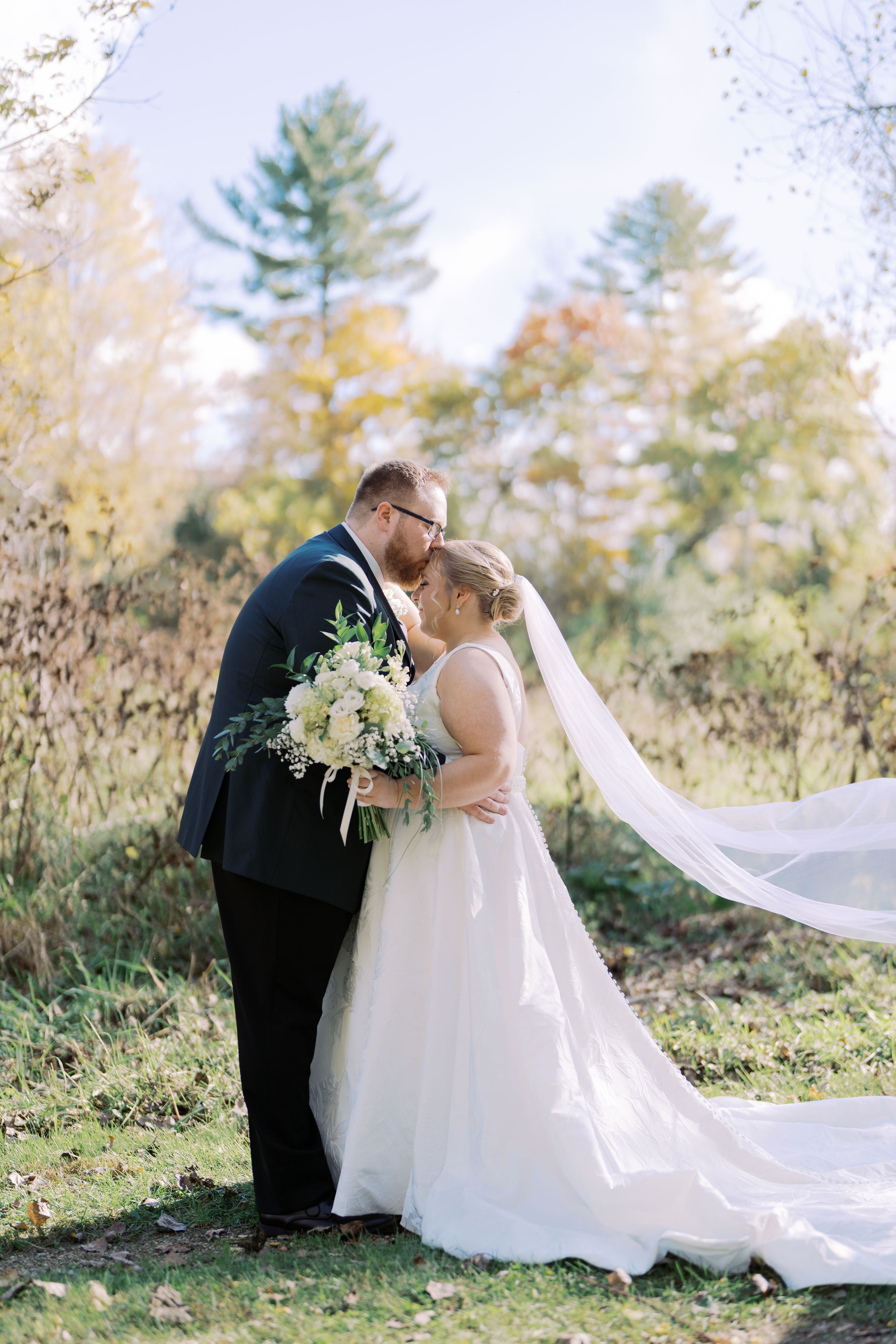 A romantic outdoor wedding scene with a flowing white dress and veil against a natural forest backdrop.