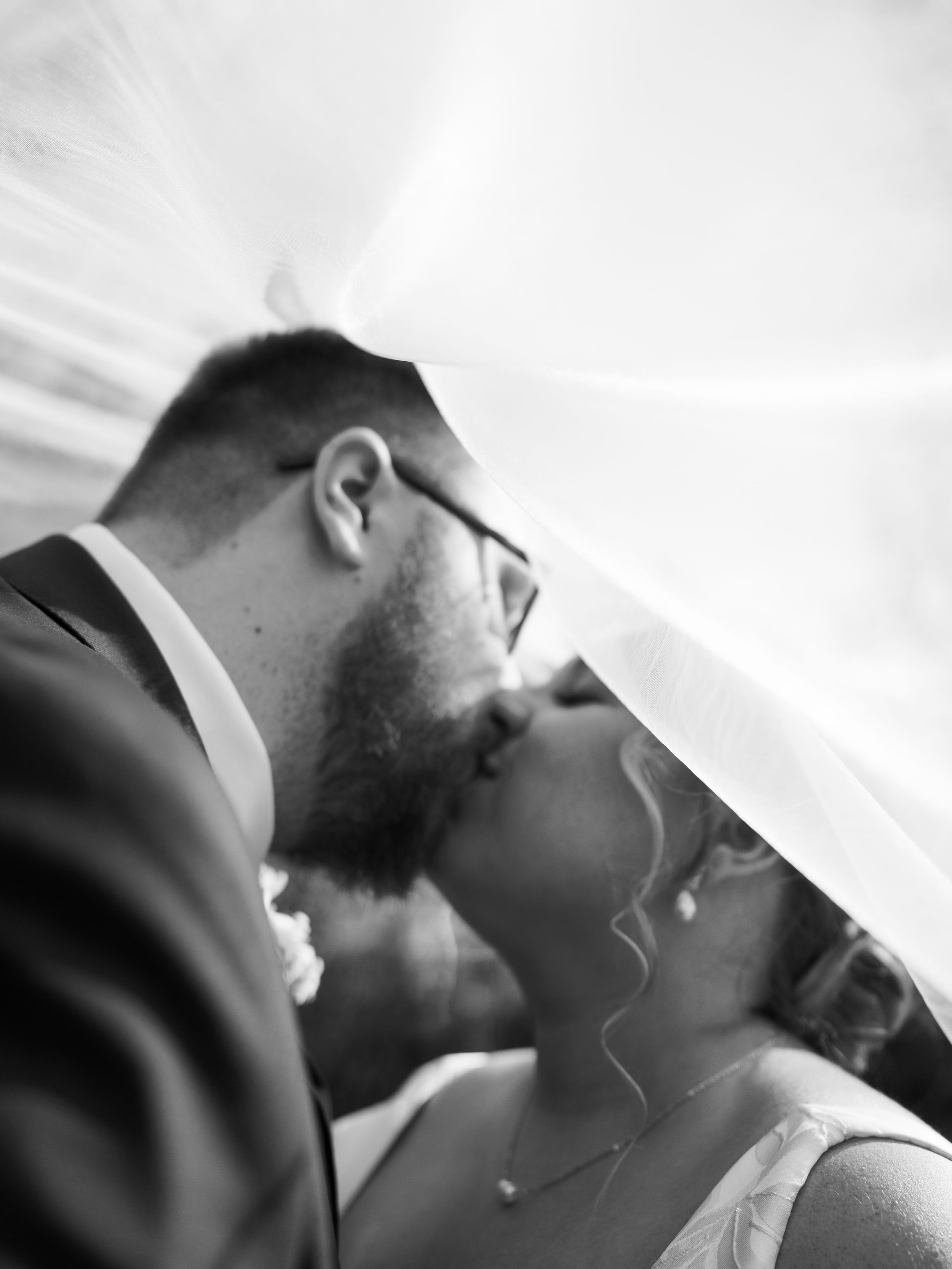 A romantic black and white wedding photo sequence showing a couple sharing an intimate kiss.