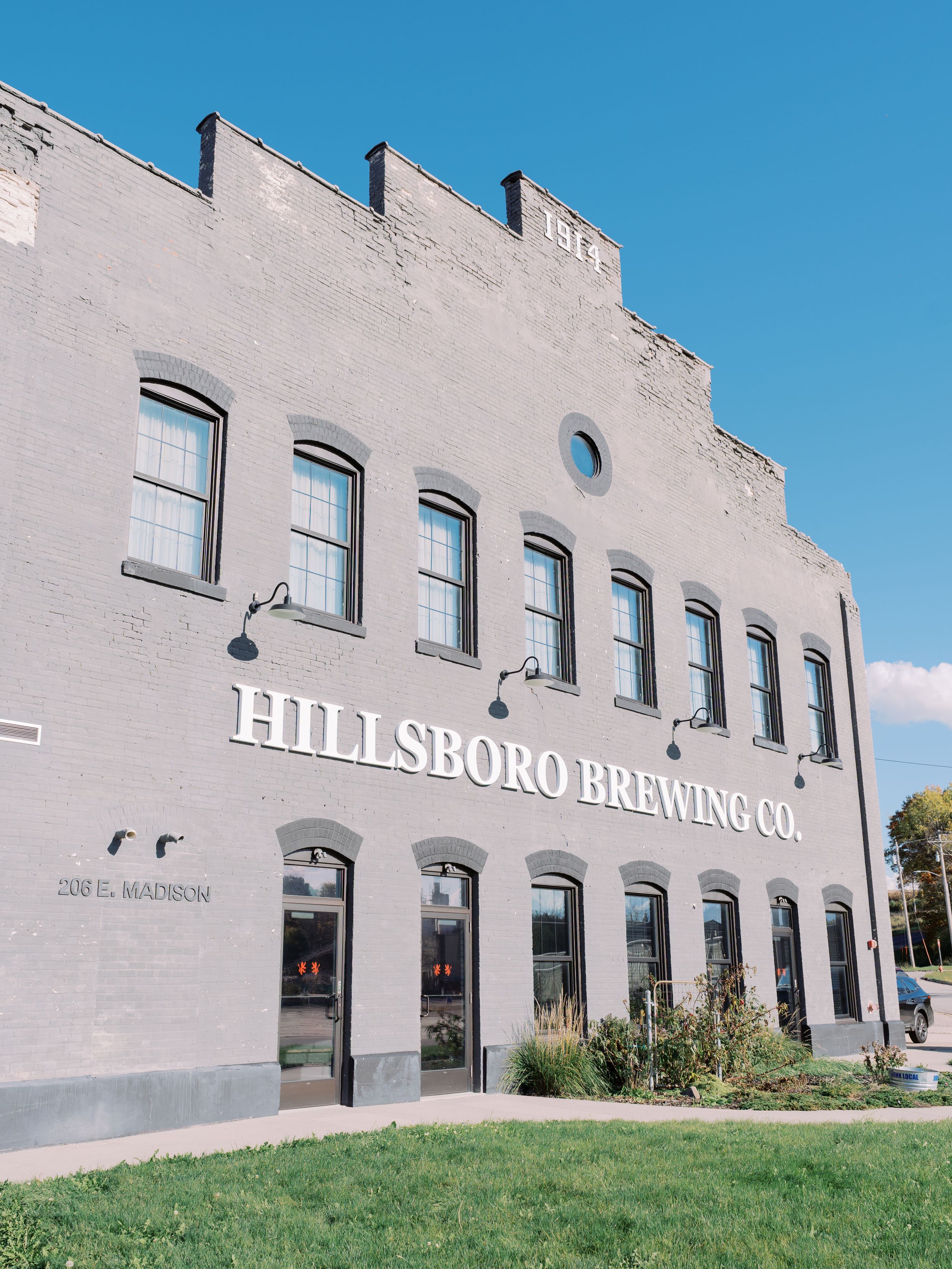 Exterior view of Hillsboro Building with white stucco walls and arched windows against a bright blue sky.