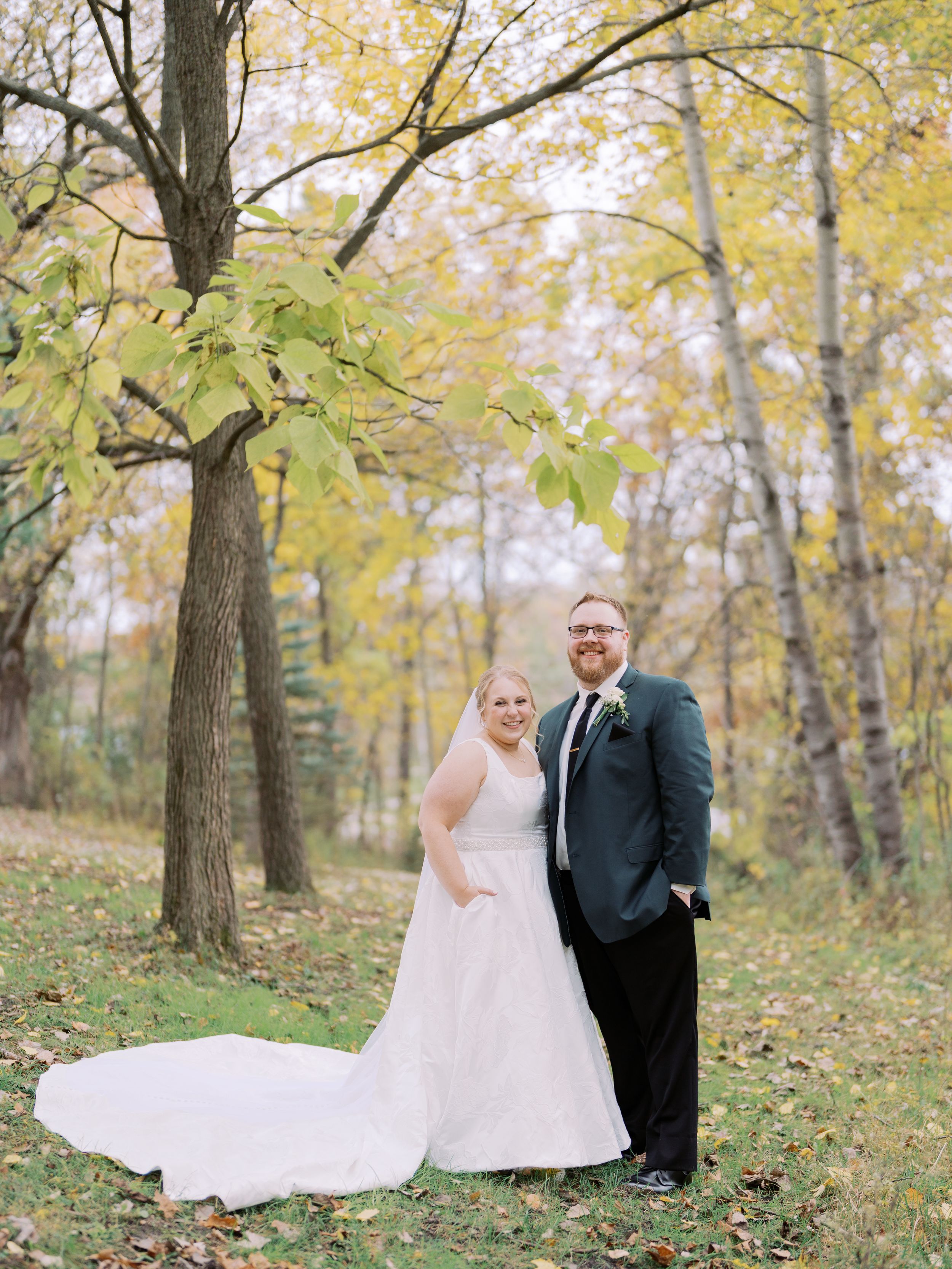 A couple shares romantic moments in a fall forest setting with golden leaves and natural lighting.