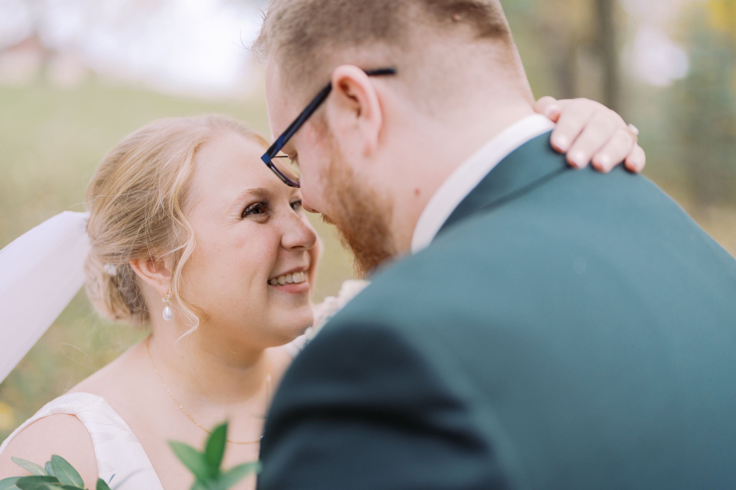 A couple in wedding attire shares an intimate moment outdoors during their special day.