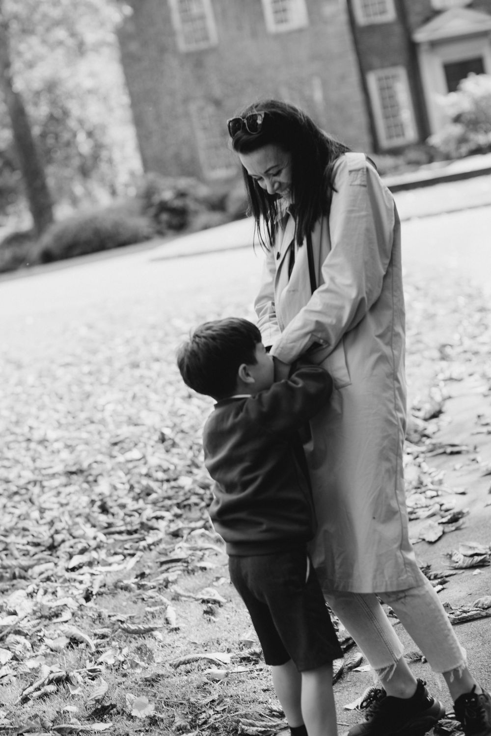 Black and white photo series showing a tender interaction between parent and child on a leaf-covered ground.
