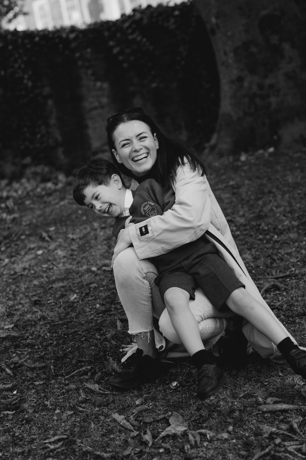 Black and white photo sequence showing playful movement and laughter while rolling on the ground outdoors.