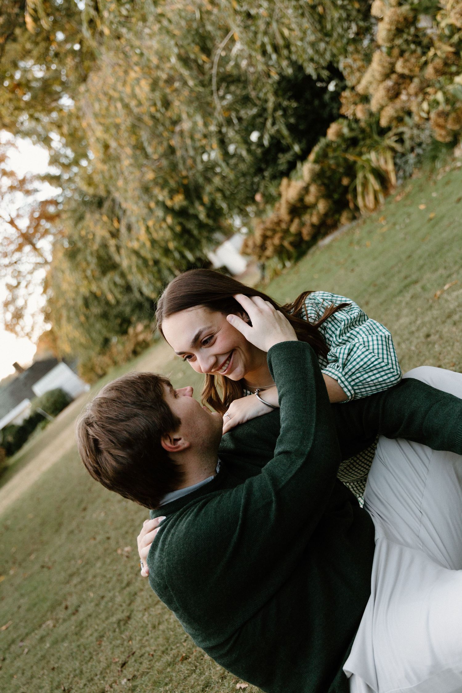 A couple shares a tender moment lying together on grass during a romantic outdoor photoshoot.