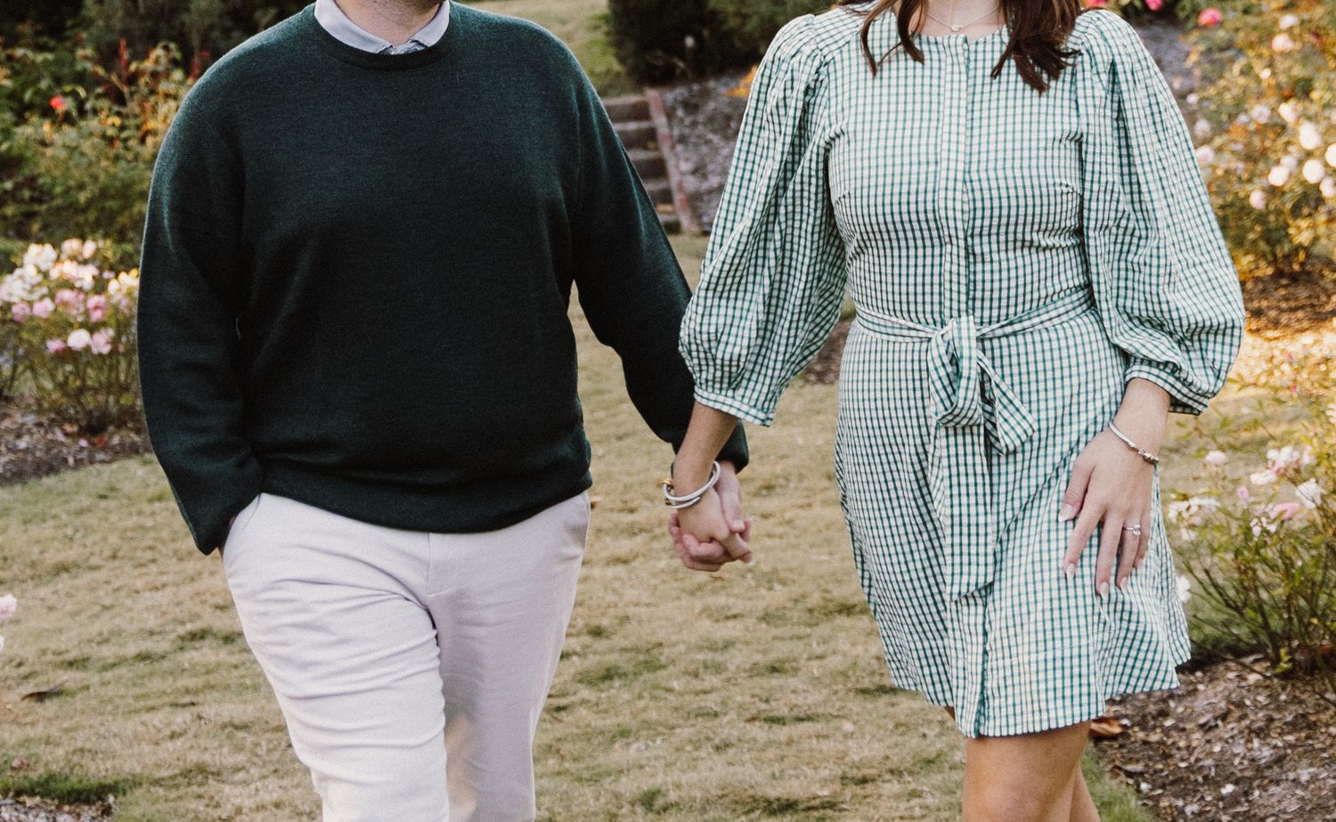 A couple walking hand in hand through a golden autumn field wearing coordinated casual outfits.